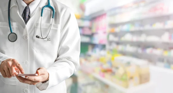 Farmacêutico masculino usando telefone celular na farmácia . — Fotografia de Stock