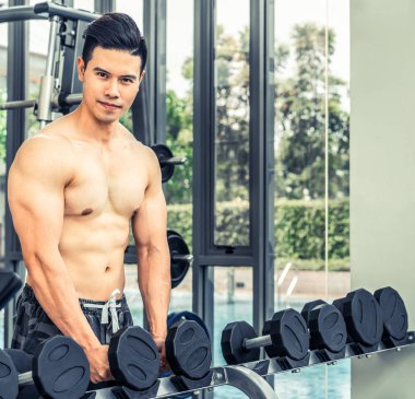 Kaslı adam vücut geliştirmeci dumbbells ile eğitim.