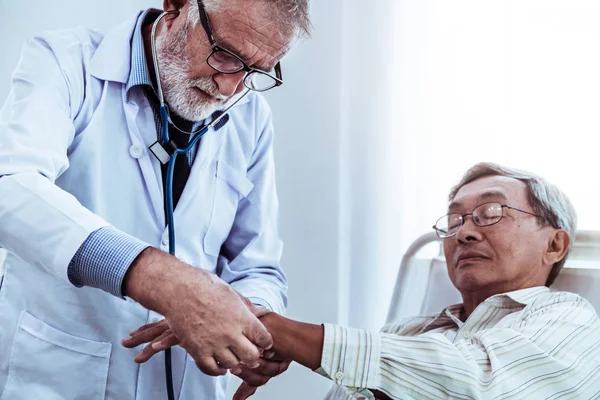 Mature doctor and senior patient in hospital ward. — Stock Photo, Image