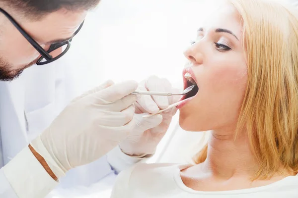 Молодой дантист осматривает пациента в стоматологической клинике . — стоковое фото