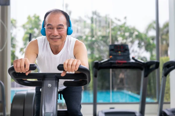 Senior man oefening op fiets machine in fitnesscentrum — Stockfoto