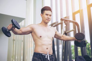 Kaslı adam vücut geliştirmeci dumbbells ile eğitim.