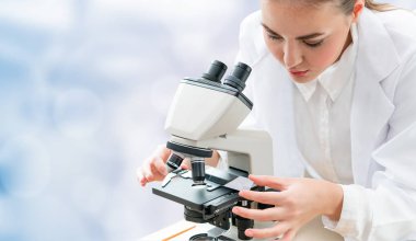 Bilim adamı araştırmacı laboratuvarda mikroskop kullanır