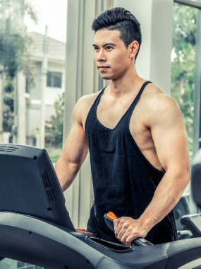 Spor salonunda koşu bandıüzerinde çalışan sportif koşucu.