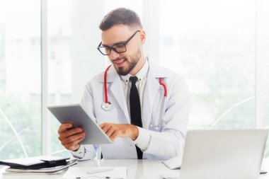 Hastanede tablet bilgisayar üzerinde çalışan doktor.