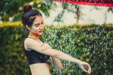 Tatil beldesinde yüzme havuzunda duş alan kadın.