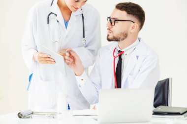 Hastanedeki doktor ortağıyla bilgisayar başında çalışıyor.