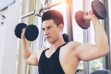 Kaslı adam vücut geliştirmeci dumbbells ile eğitim.