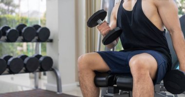 Kaslı adam vücut geliştirmeci dumbbells ile eğitim.
