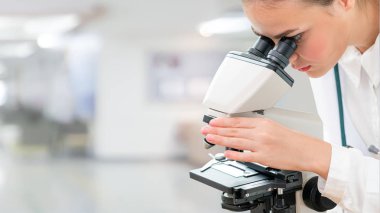 Bilim adamı araştırmacı laboratuvarda mikroskop kullanır