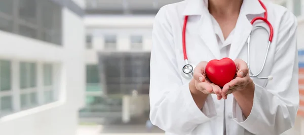 Γιατρός που κρατάει κόκκινη καρδιά στο γραφείο του νοσοκομείου.. — Φωτογραφία Αρχείου