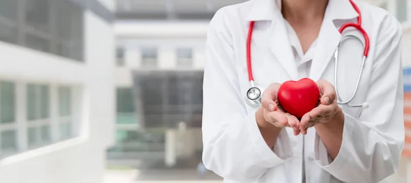 Doctor sosteniendo un corazón rojo en la oficina del hospital . — Foto de Stock