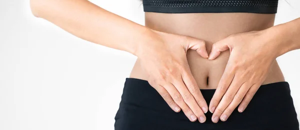 Mujer en ropa deportiva hace gesto de corazón en el abdomen — Foto de Stock