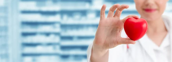 Doctor sosteniendo un corazón rojo en la oficina del hospital . — Foto de Stock