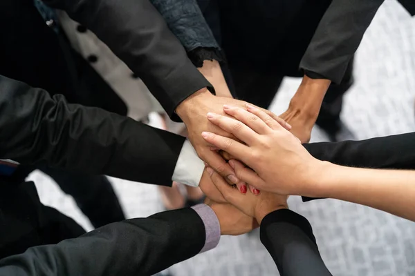 Many happy business people stacking hands together with joy and success. Company employee celebrate after finishing successful work project. Corporate partnership and achievement concept.