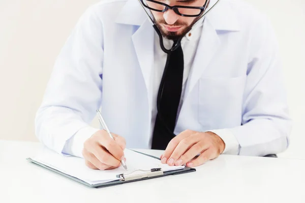 Arzt im Krankenhaus schreibt auf ein Papierdokument. — Stockfoto