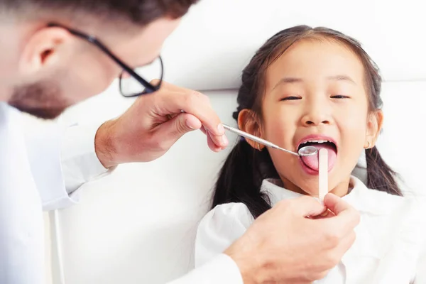 Dentista examinando dientes infantiles en clínica dental . — Foto de Stock