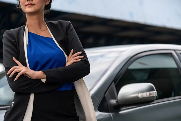 Confident business woman standing beside the car.