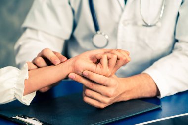 Hastane ofisinde hastayı muayene eden genç doktor.