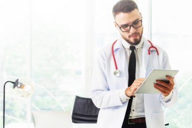 Hastanede tablet bilgisayar üzerinde çalışan doktor.