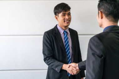 İş adamları konsepti kabul ediyor. Asyalı iş adamı ofis toplantı odasında başka bir işadamıyla tokalaşıyor..