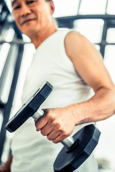 Uomo anziano che solleva manubri in palestra fitness . — Foto Stock