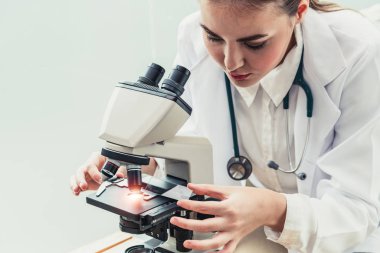 Hastane laboratuvarında mikroskop kullanan doktor.