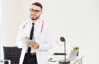 Hastanede tablet bilgisayar üzerinde çalışan doktor.