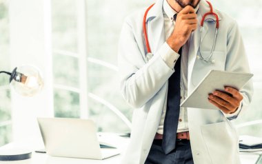 Hastanede tablet bilgisayar üzerinde çalışan doktor.