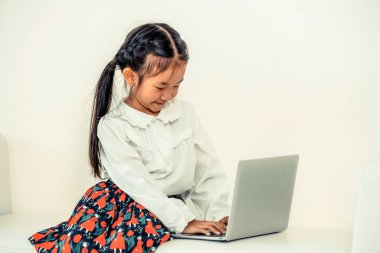 Küçük çocuk beyaz kanepeüzerinde dizüstü bilgisayar kullanarak.