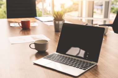 Toplantı odasındaki masada dizüstü bilgisayar var..