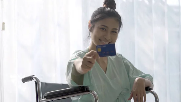 Happy patient hold credit card and smile while sitting on wheelc
