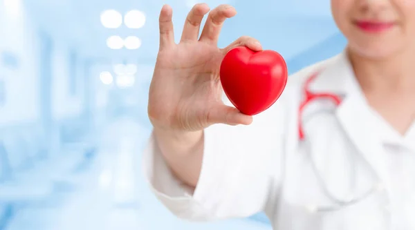 Doctor sosteniendo un corazón rojo en la oficina del hospital . — Foto de Stock