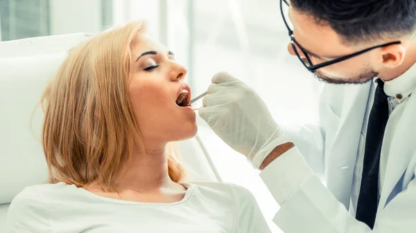 Молодой дантист осматривает пациента в стоматологической клинике . — стоковое фото