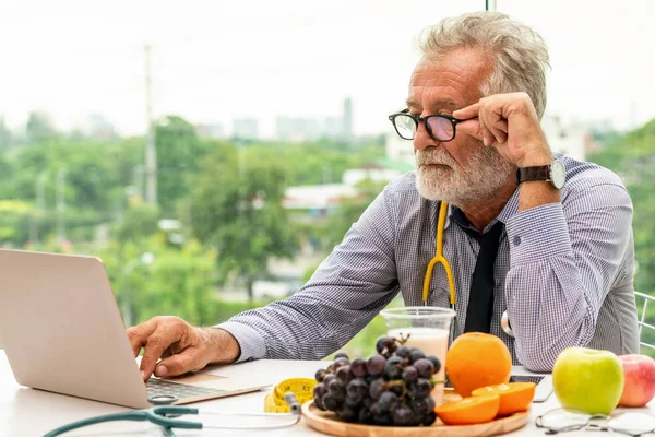 Senior férfi táplálkozási orvos dolgozik laptop. — Stock Fotó