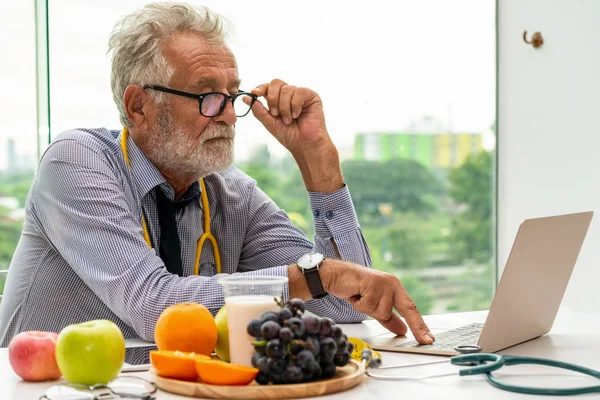 Dizüstü bilgisayar üzerinde çalışan kıdemli erkek beslenme uzmanı doktor. — Stok fotoğraf