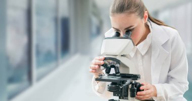 Bilim adamı araştırmacı laboratuvarda mikroskop kullanır