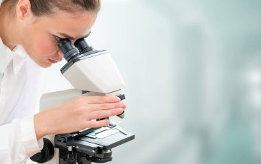 Bilim adamı araştırmacı laboratuvarda mikroskop kullanır