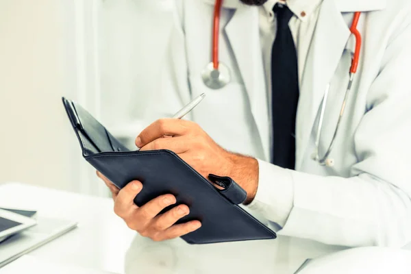 Médico lendo enquanto escrevia nota em um livro . — Fotografia de Stock