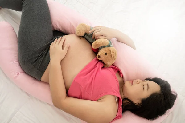 Šťastná těhotná žena spí na posteli v ložnici. — Stock fotografie