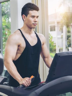 Spor salonunda koşu bandıüzerinde çalışan sportif koşucu.