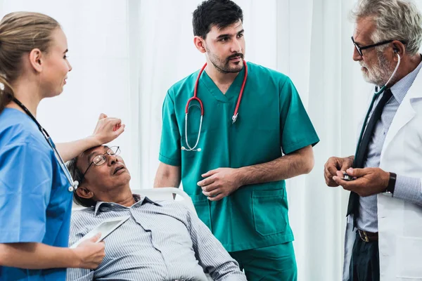 病院病棟のベッドに横たわる高齢者男性患者の世話をする医師チーム 医療医療従事者サービス治療コンセプト — ストック写真
