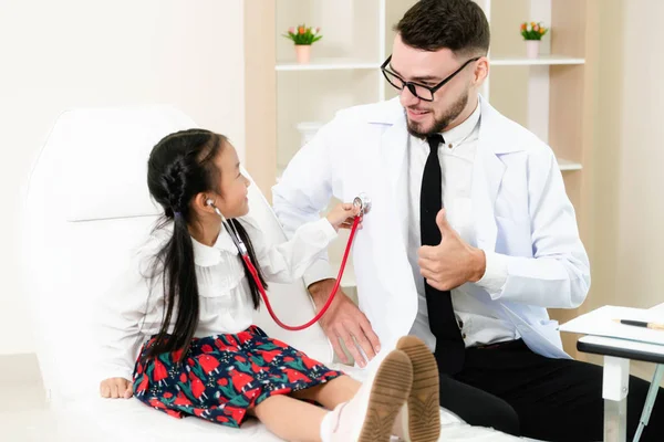 Feliz niña visita al médico en el consultorio del hospital . — Foto de Stock