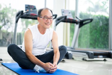 Kıdemli adam fitness merkezinde vücut germe yapmak.