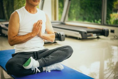 Fitness salonunda yaşlı adam uygulama yoga.