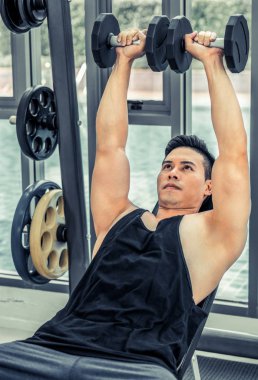 Kaslı adam vücut geliştirmeci dumbbells ile eğitim.