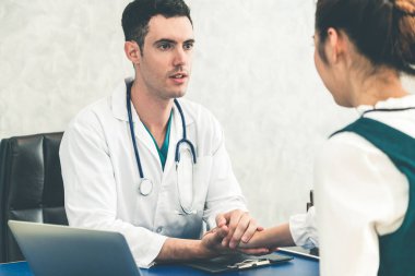 Hastane ofisinde hastayı muayene eden genç doktor.