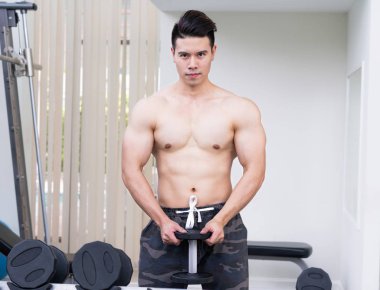 Kaslı adam vücut geliştirmeci dumbbells ile eğitim.