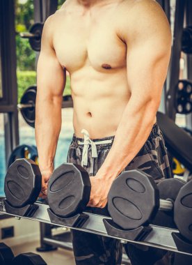 Kaslı adam vücut geliştirmeci dumbbells ile eğitim.