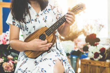 Stüdyoda ukulele çalan mutlu kadın müzisyen.